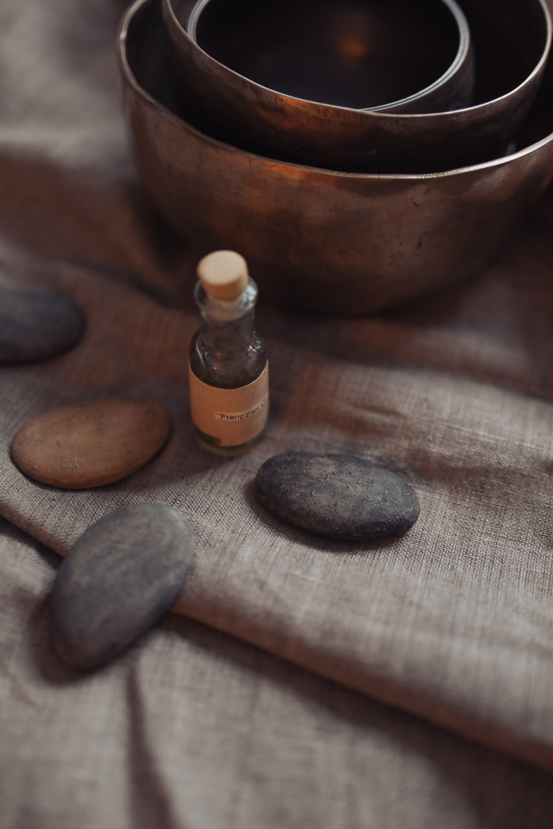 Singing Bowl with Stones and Massage Oil on Gray Cloth